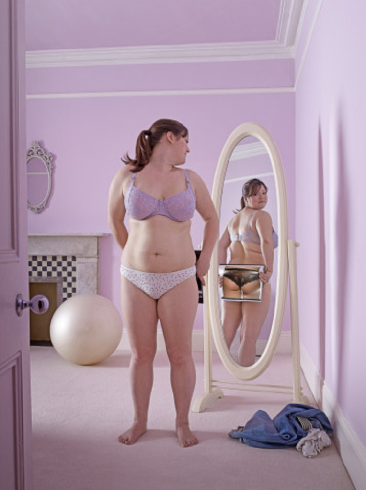 В зеркале вижу себя другой. Толстушка в зеркале. Толстая девушка перед зеркалом. Полная женщина смотрится в зеркало.